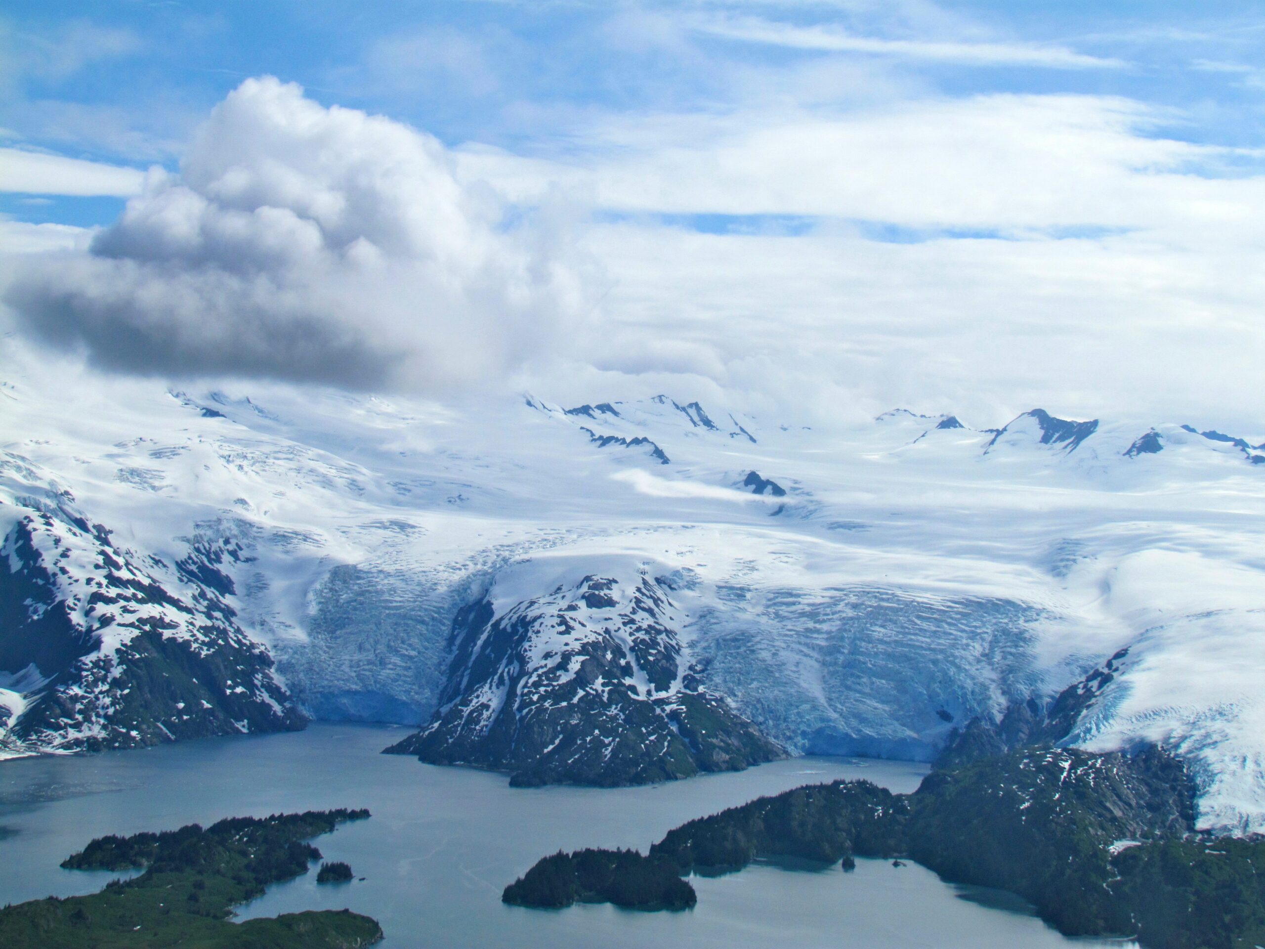 Scenic aerial view of the glaciers and fjords in College Fjord, Alaska surrounded by snow-capped mountains and blue waters.